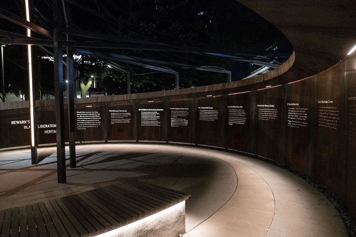 The completed learning wall after dark, with illuminated text and the seating area inside